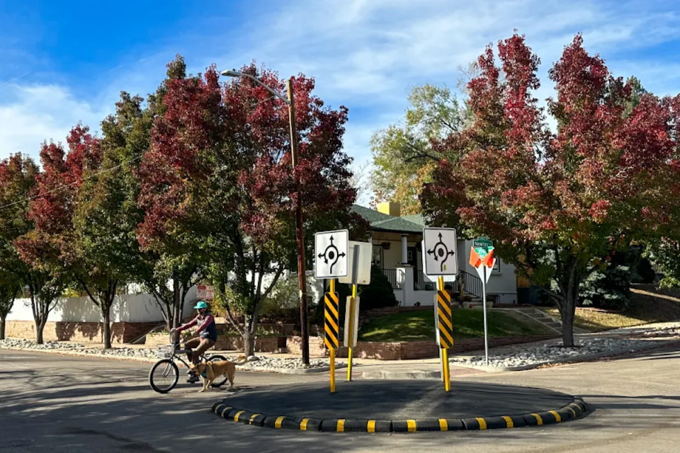 Cyclist with dog passing through a small neighborhood traffic circle in Denver, Colorado.